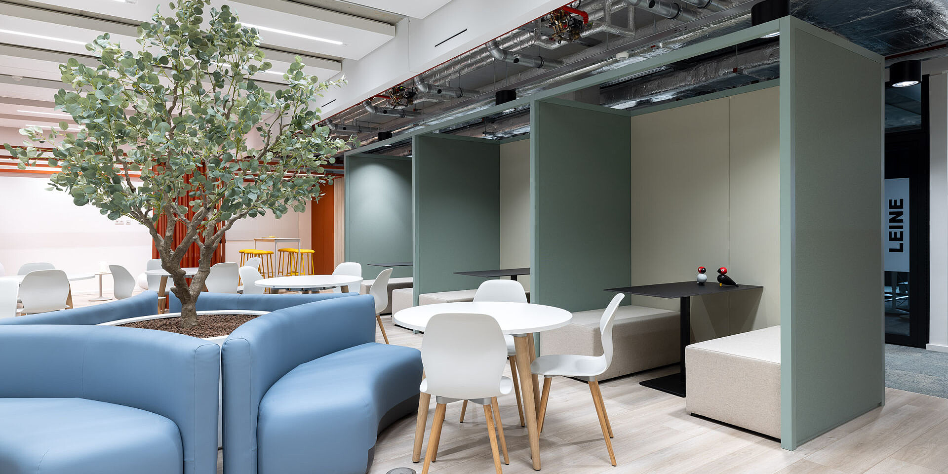 Bistro area at Veolia with white se:spot designer chairs and round se:assist tables, large tree in the centre, bright, modern canteen environment 