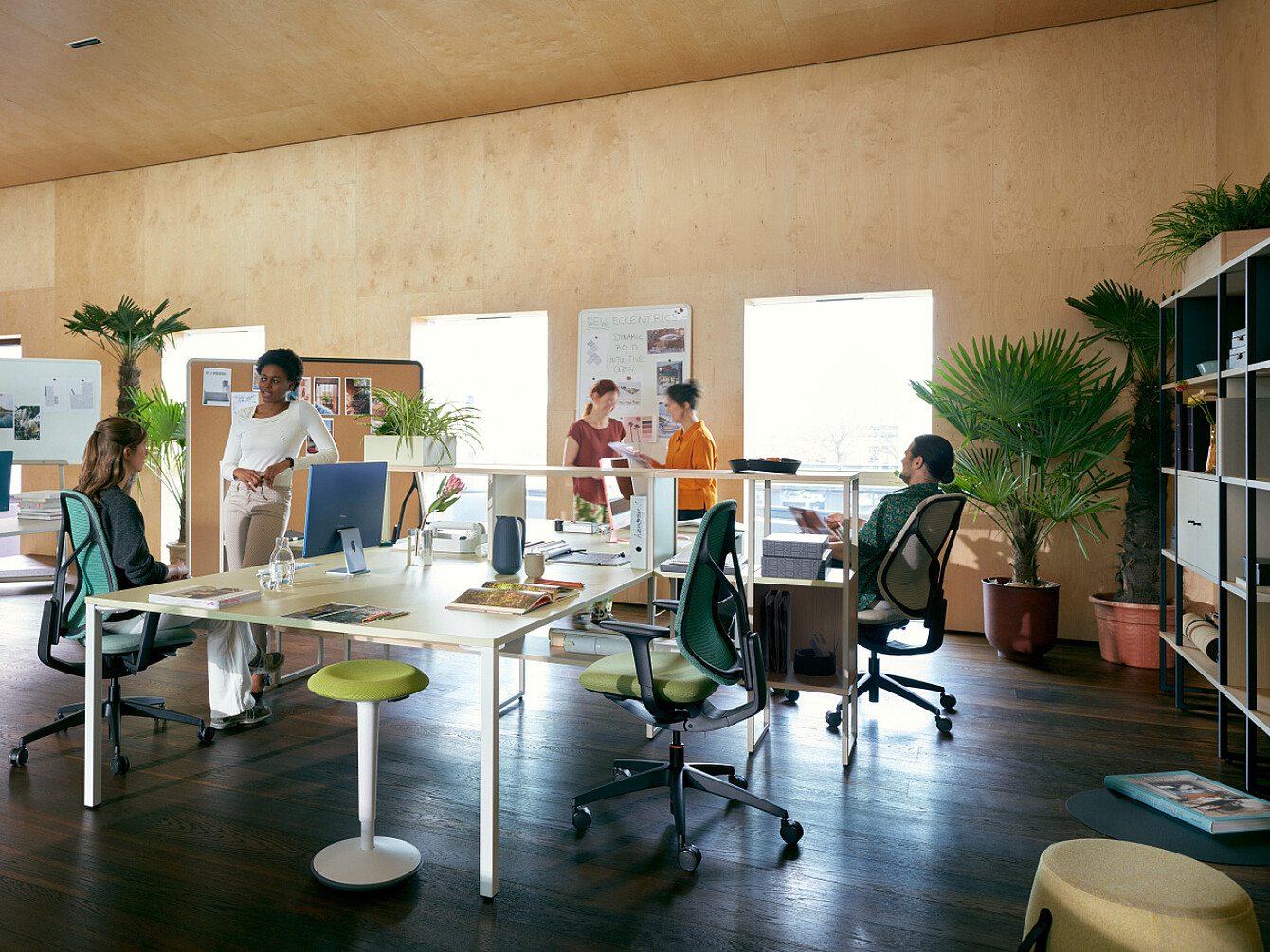 Oficina abierta con luz natural, plantas, sillas ergonómicas y empleados colaborando, lo que refleja un lugar de trabajo centrado en el bienestar y el apoyo integral.