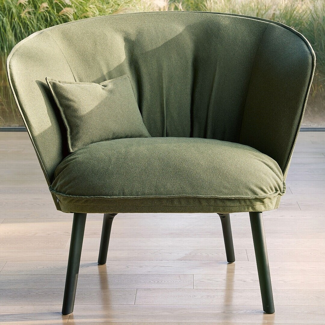 Green armchair with high backrest and a cushion in front of a window showing plants outside