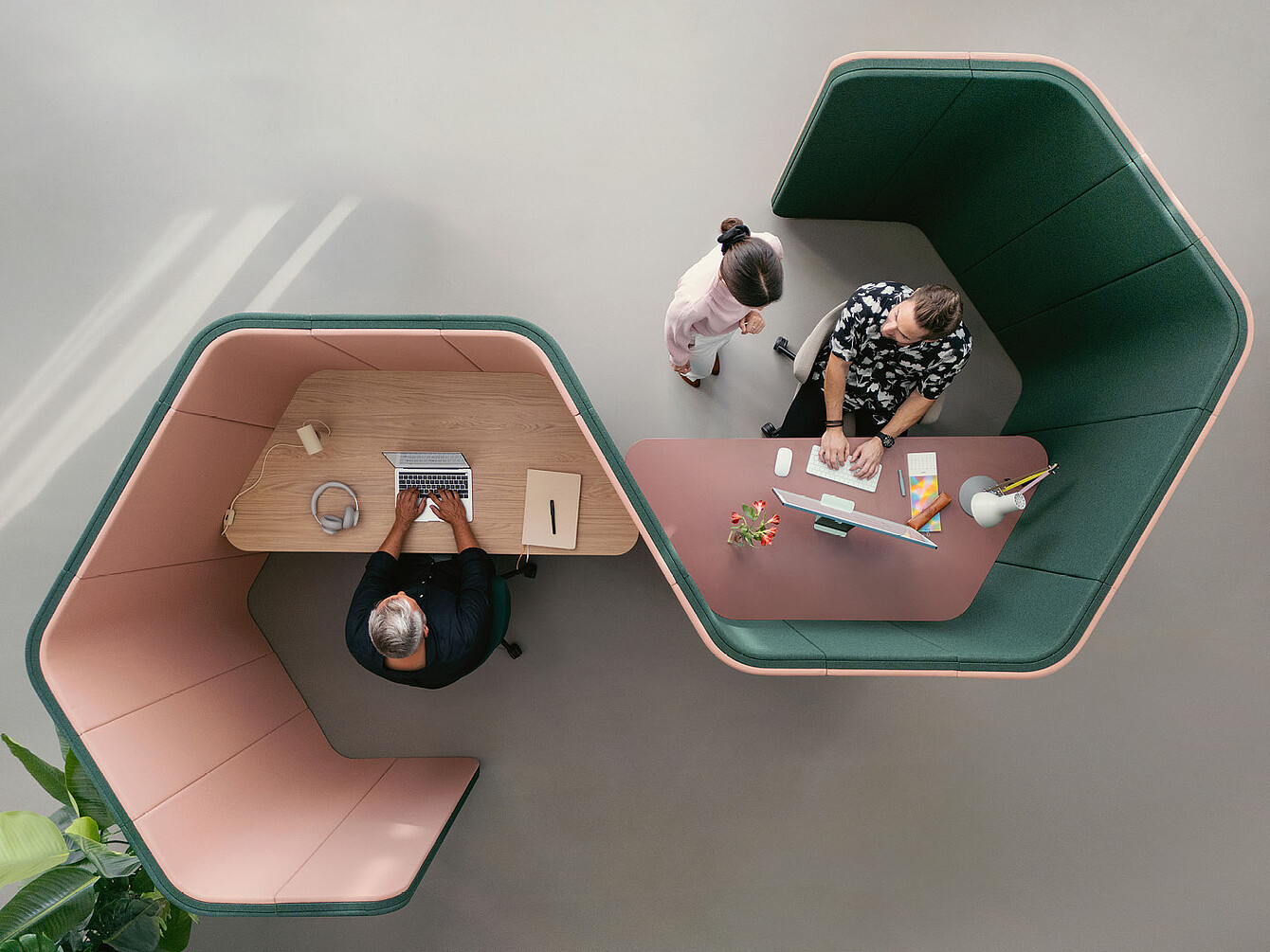 Dos personas trabajando en cabinas hexagonales adyacentes de se:hive, una con un ordenador portátil y otra con un ordenador de sobremesa, vistas desde arriba