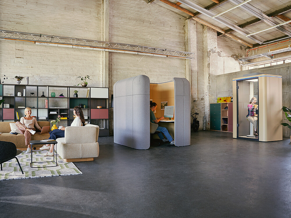 Ampio spazio ufficio moderno in stile industriale, con diverse aree di lavoro, seduta e relax.
