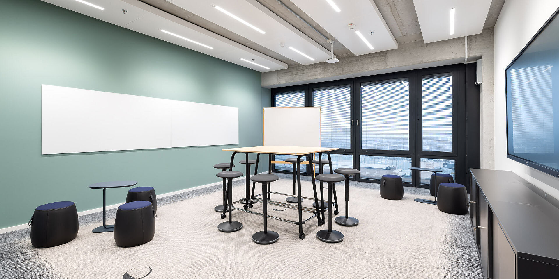 Modern meeting room with se:lab high desk workshop table, se:fit standing seats and se:dot stools for agile working and collaboration. 