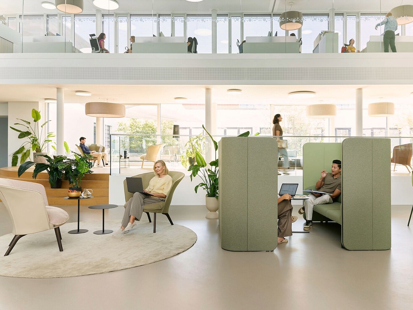 Espacio de oficina moderno con asientos abiertos, cabinas acústicas de respaldo alto y luz natural procedente de grandes ventanas