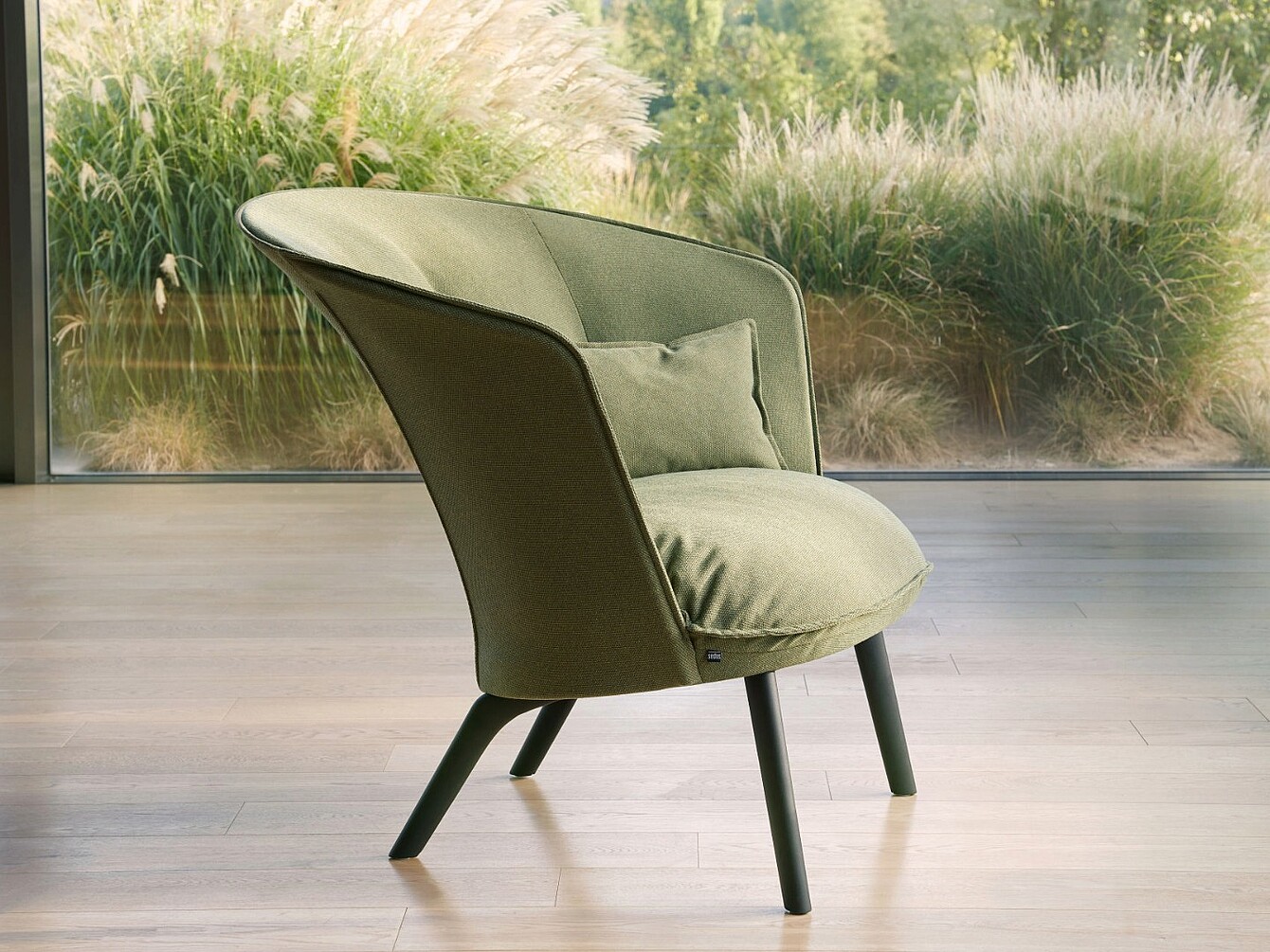 Comoda poltrona di design con rivestimento in tessuto verde davanti a un’ampia vetrata che mostra le piante del giardino