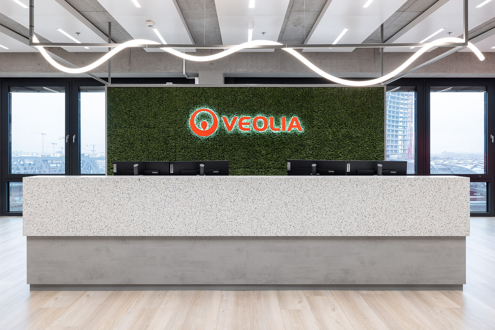 The cover image of the Veolia Hamburg reference page on the Sedus website: reception desk in a modern office with green wall background and bright Veolia logo in orange and white.