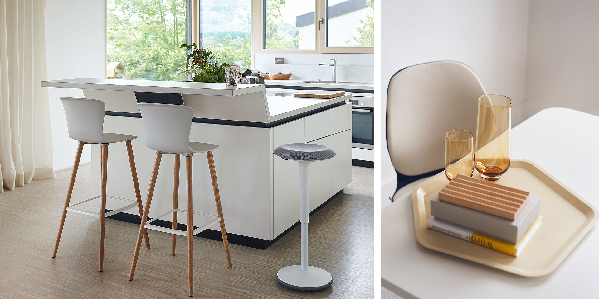 Modern kitchen area with white island, three barstools, and a view of green landscape through the window.