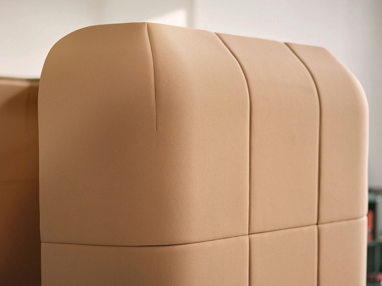 Primer plano de un panel tapizado en color beige con costuras verticales y horizontales que forman un patrón de cuadrícula