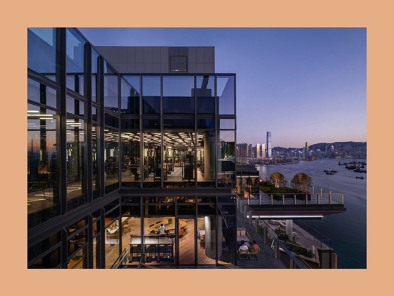Immeuble moderne de plusieurs étages avec des murs en verre donnant sur un paysage urbain au bord de l’eau au crépuscule 