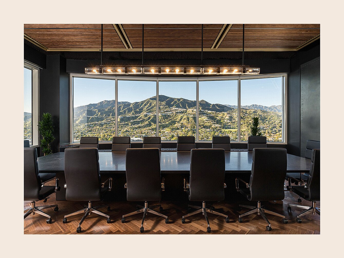 Salle de conférence avec une longue table entourée de chaises de bureau face à de grandes fenêtres donnant sur un paysage montagneux